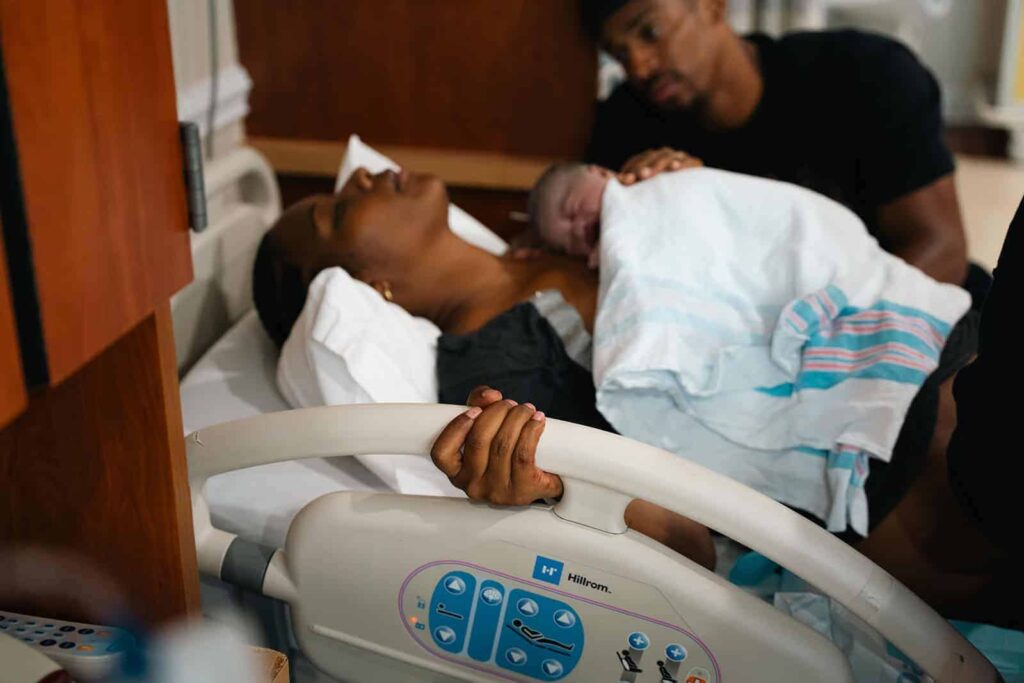 Labor and delivery photography session capturing the intimate first touch between mother and newborn